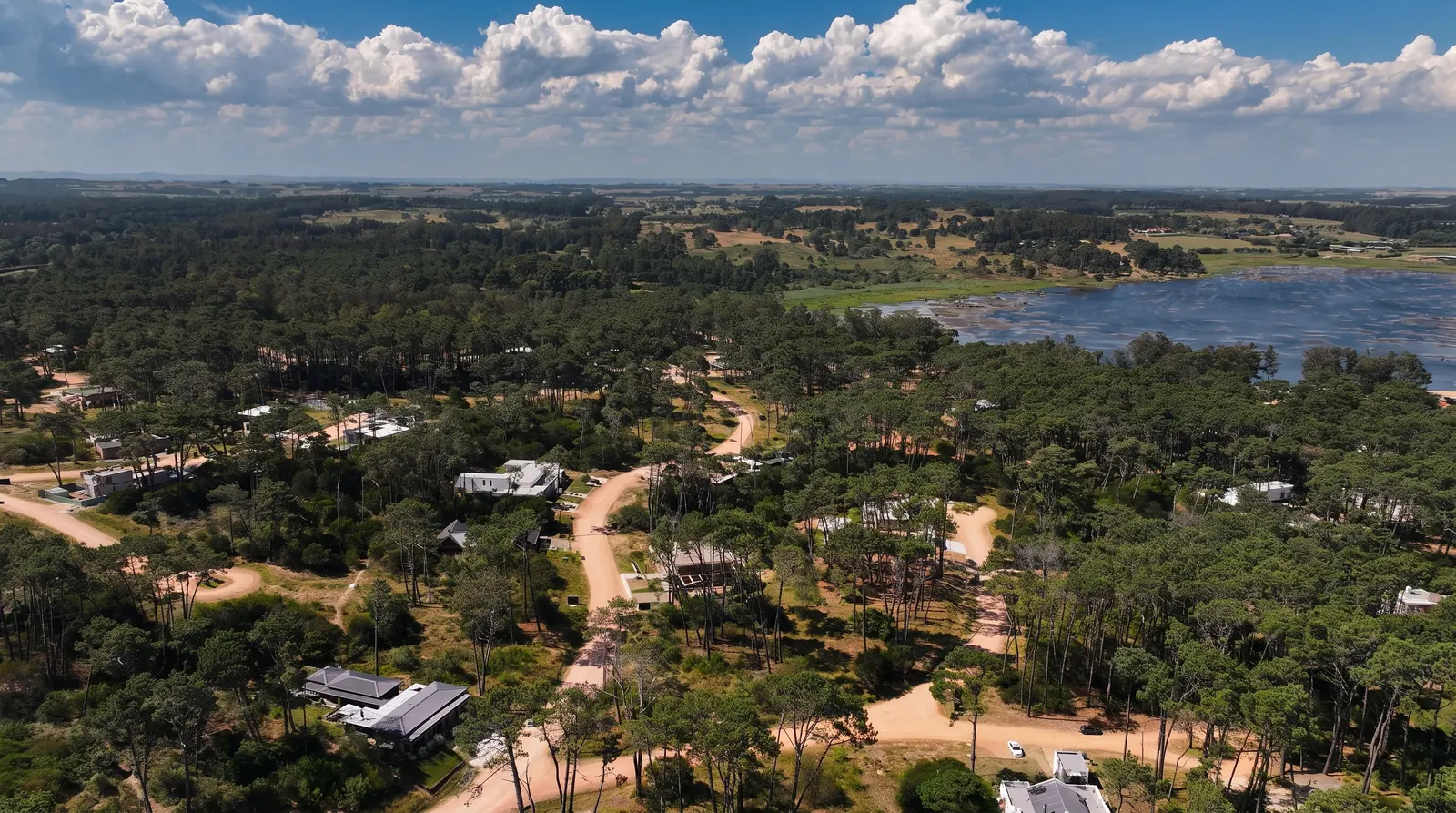 Casas construidas entre los pinos de Reserva Montoya, con Laguna Blanca al fondo
